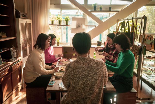 テーブルを囲んで食事をする人たちとカフェ「キッサテンホケンシツ」の店内